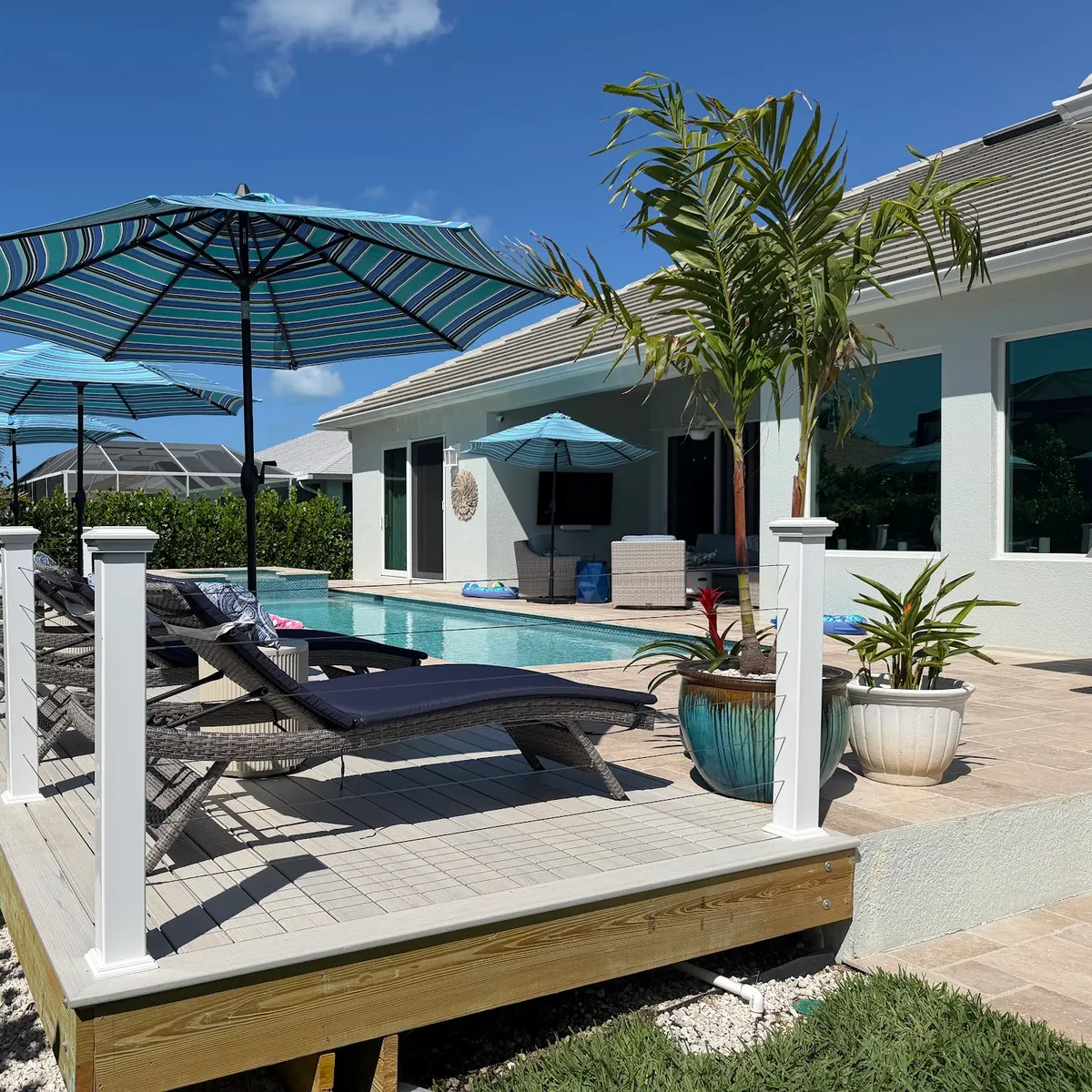 A composite pool deck with white posts and loungers