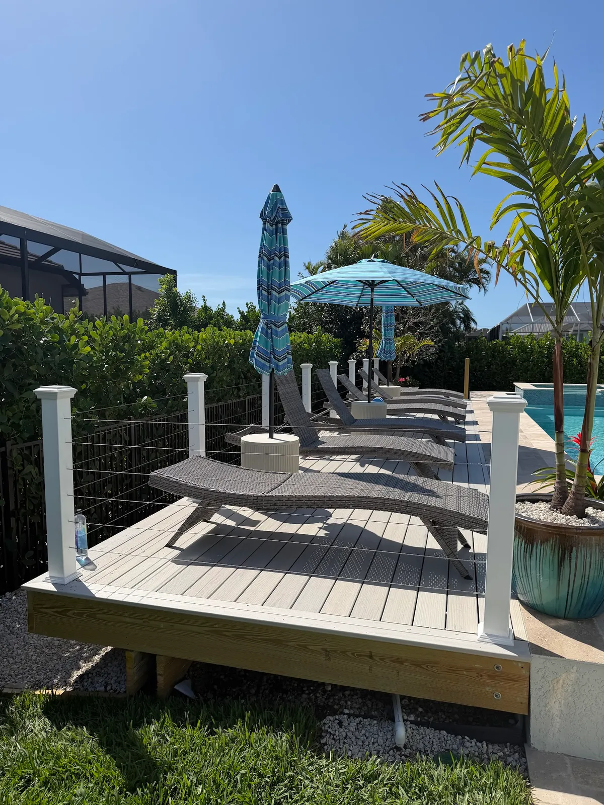 A ground-level composite deck beside a pool, seen down its length